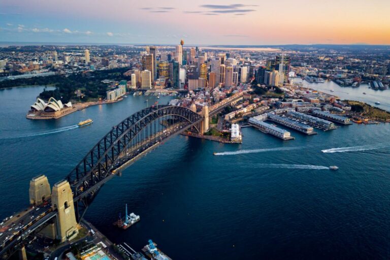 Aerial view of Sydney Harbour Bridge and Opera House at sunset.