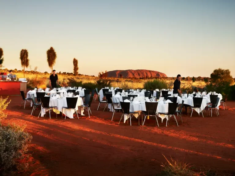 Outdoor dining setup at sunset near Uluru.