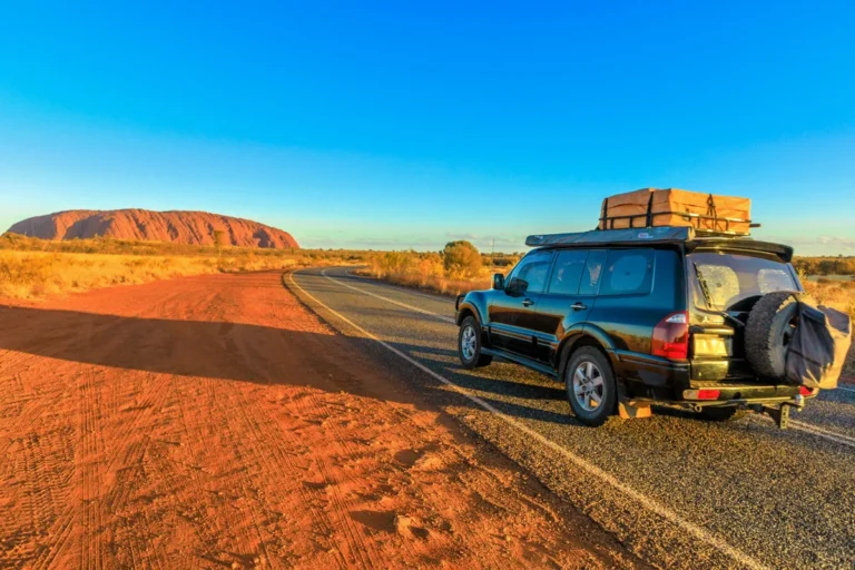 Car on road trip near Uluru in the Australian Outback