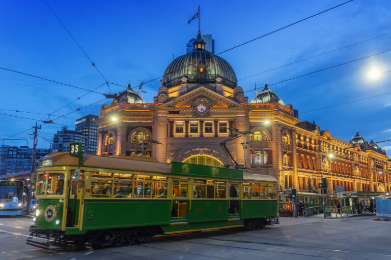 Historic Flinders Street Station with tram at night in Melbourne.