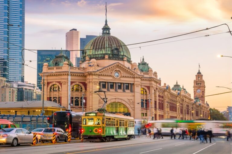 Flinders Street Station with trams and bustling city life in Melbourne.