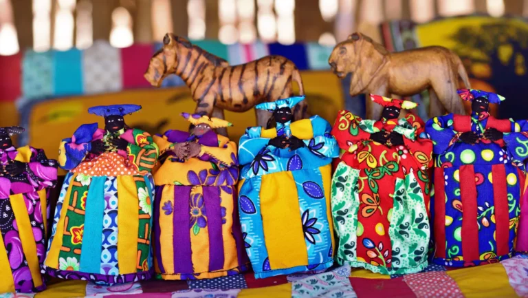 Colorful African dolls and wooden animal carvings at a craft market.