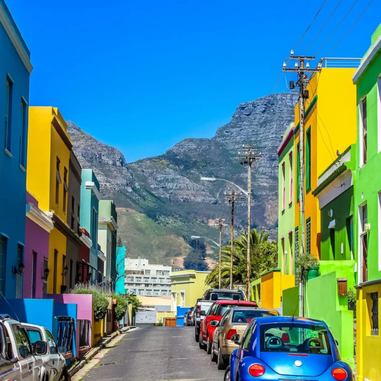 Colorful houses and cars in Bo-Kaap, Cape Town with mountains in the background