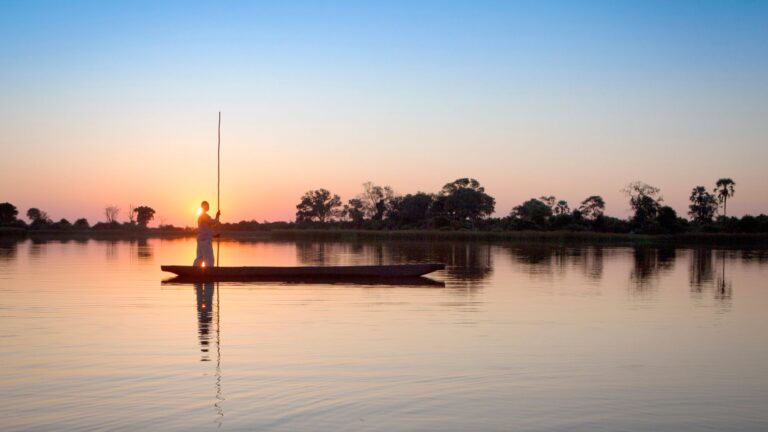 Person on a mokoro at sunset in the Okavango Delta