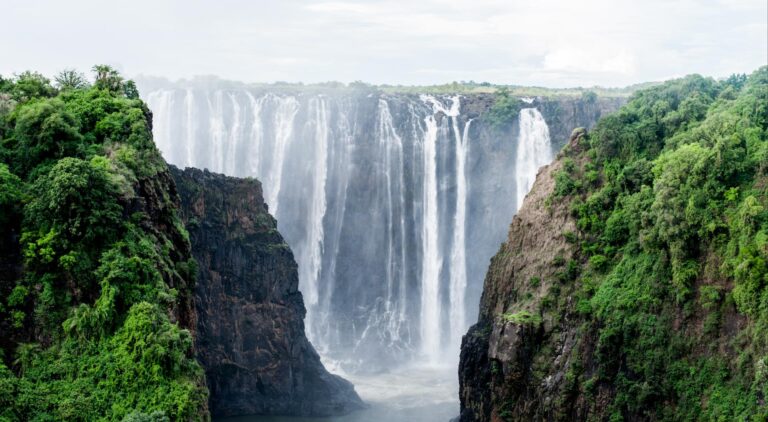 Majestic view of Victoria Falls with lush green cliffs.