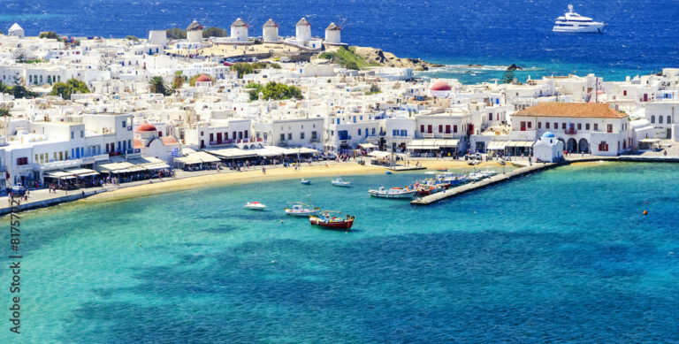 Aerial view of Mykonos town with iconic windmills and boats.