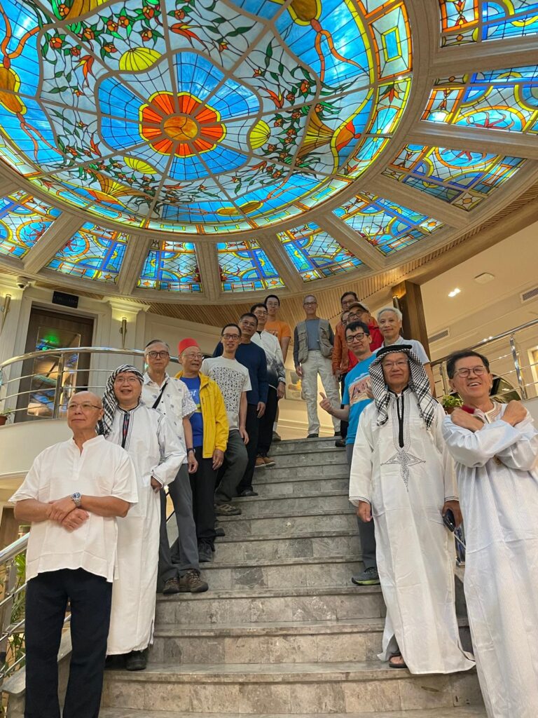 Group of travelers on a staircase under a stained glass ceiling.