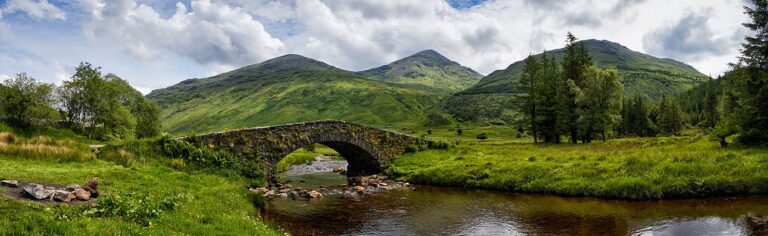 Scenic view of Loch Lomond with stone bridge and lush mountains