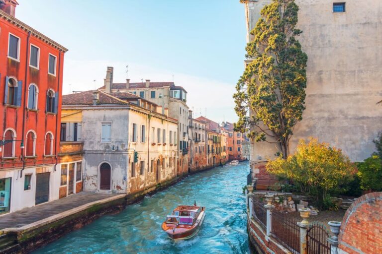 A boat navigating a narrow Venice canal lined with historic buildings.