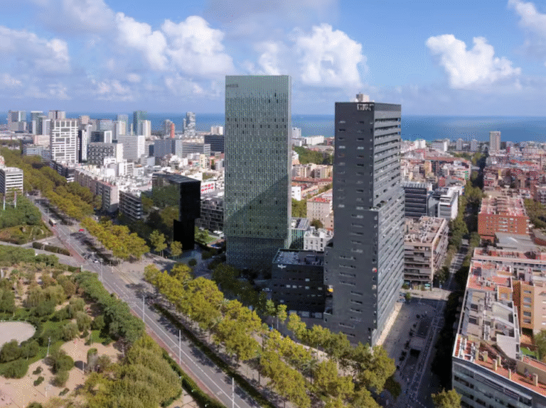 Aerial view of Barcelona's modern skyline with skyscrapers and the sea.