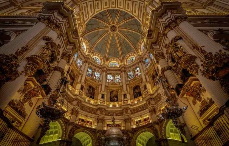 Interior of Seville Cathedral with stained glass and dome.
