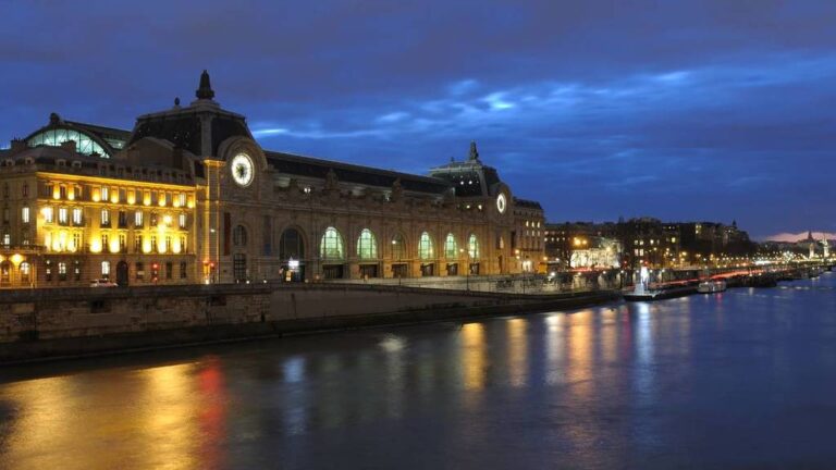 Musée d'Orsay illuminated at night by the Seine River.