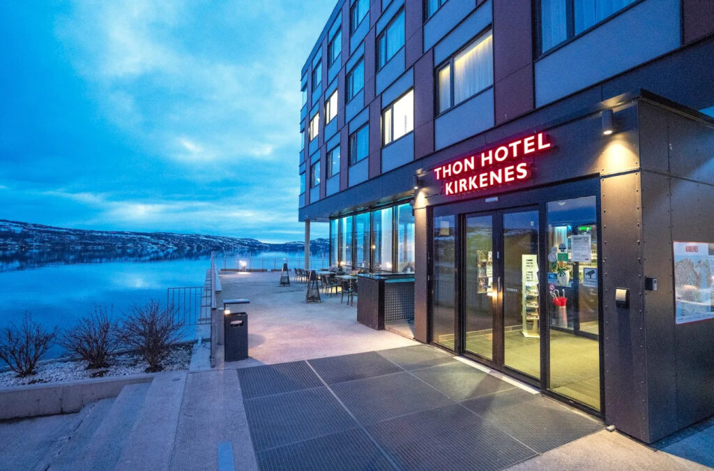 Thon Hotel Kirkenes exterior at dusk by a waterfront.