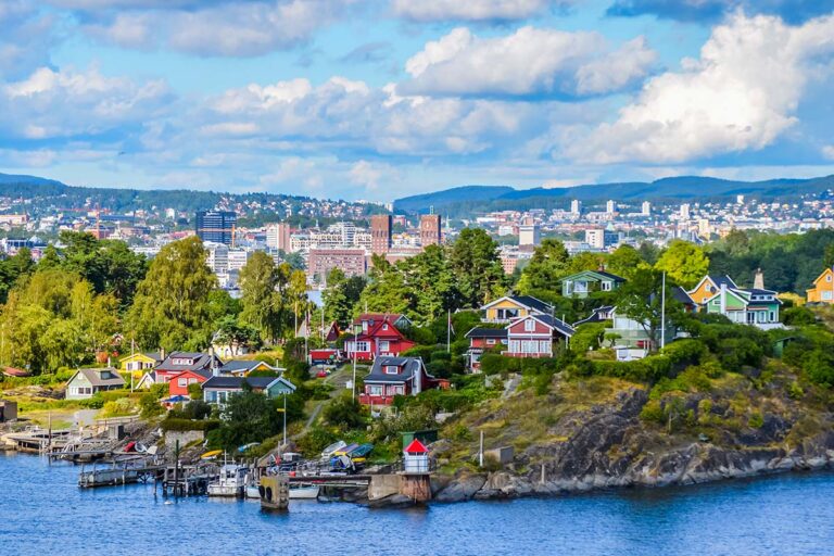 Scenic view of Oslo waterfront with colorful houses and city skyline.