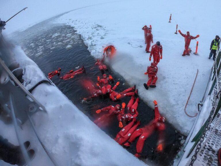 Travelers in floating suits on Arctic ice.