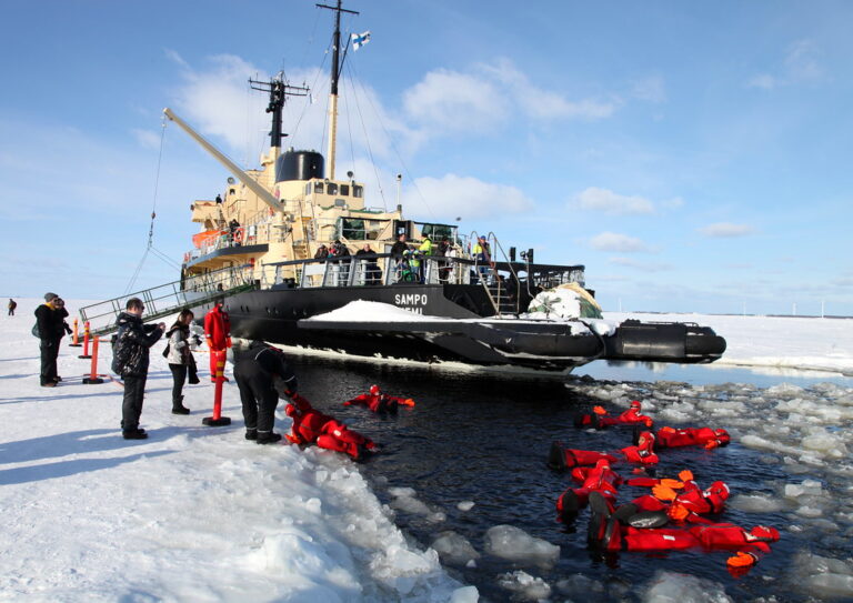 Tourists in floating suits near an Arctic icebreaker.