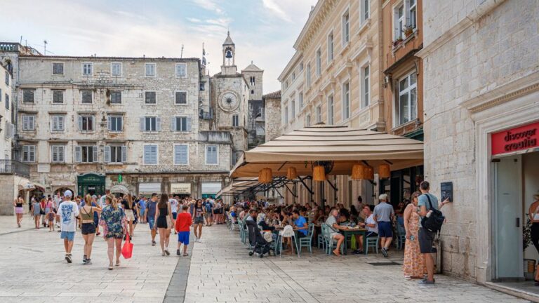 People walking and dining in Split's Old Town square.