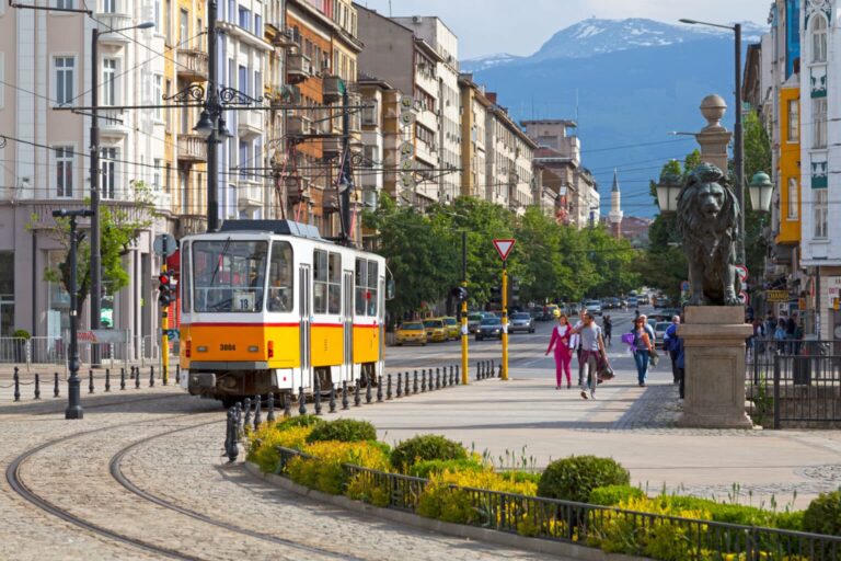 Tram on a street in Sofia, Bulgaria with pedestrians and urban buildings.