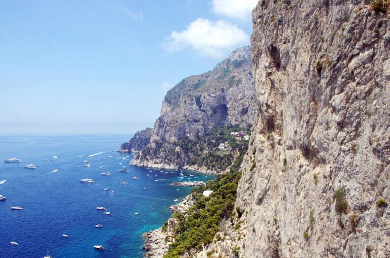 Cliffs and coastline of Capri Island with boats on the sea.