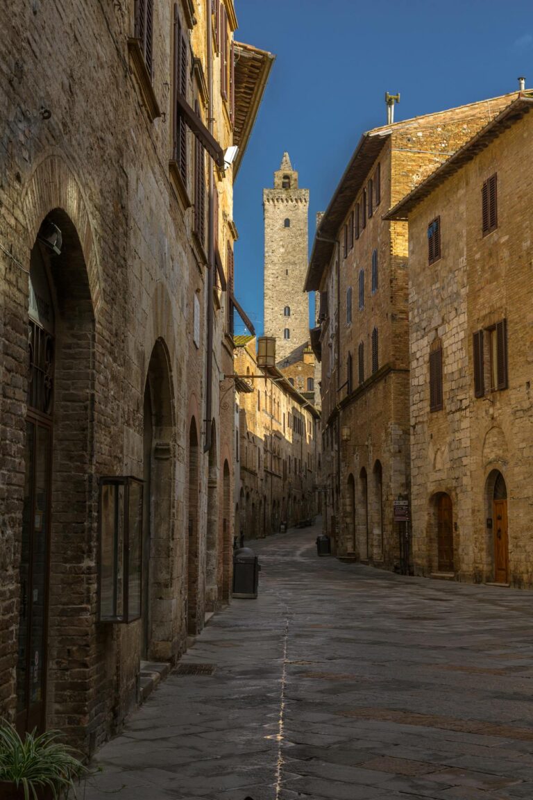 Narrow medieval street in San Gimignano with a tower in the background.