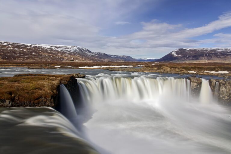 Goðafoss waterfall in Iceland with snowy mountains.