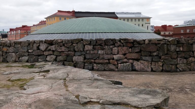 Exterior view of Helsinki's Temppeliaukio Church with stone walls and dome.