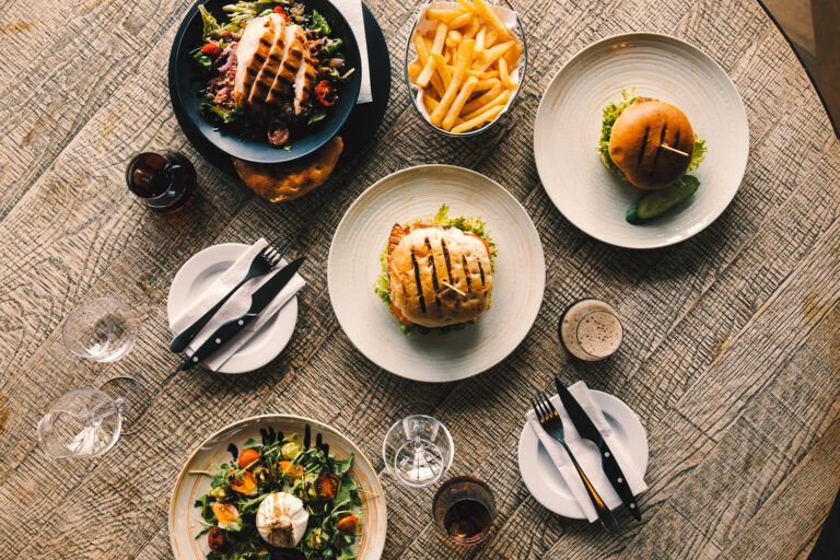 Aerial view of a dining table with burgers, salad, and fries.