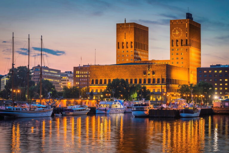 Oslo City Hall at dusk with boats in the harbor