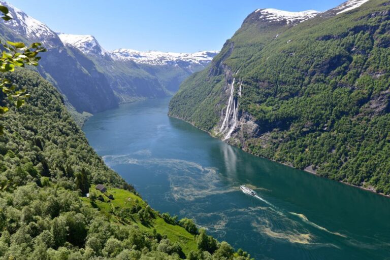 Scenic view of Geiranger Fjord with waterfall and boat