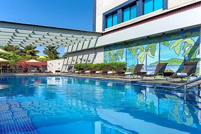 Outdoor pool area at Novotel Hotel with lounge chairs and mural.