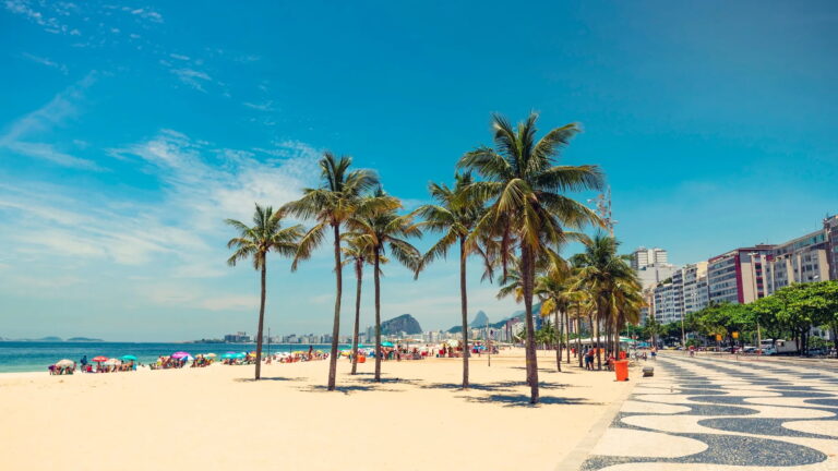 Copacabana Beach with palm trees and cityscape in Rio de Janeiro