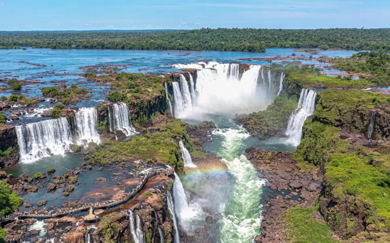 Iguazu Falls with rainbow and tourists.