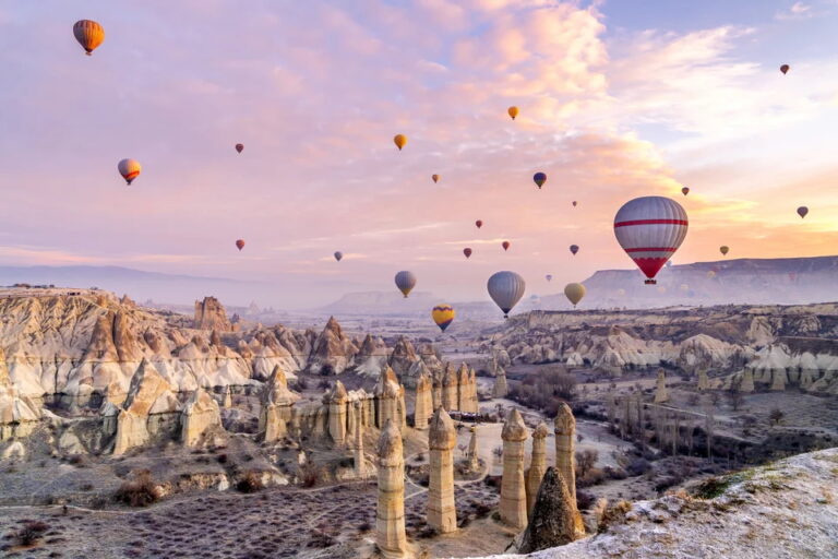 Hot air balloons over Cappadocia's unique rock formations at sunrise.