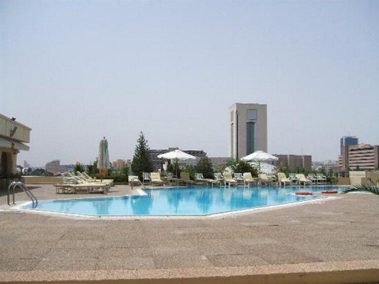 Rooftop pool at Laico Hotel in Tunis with city skyline.