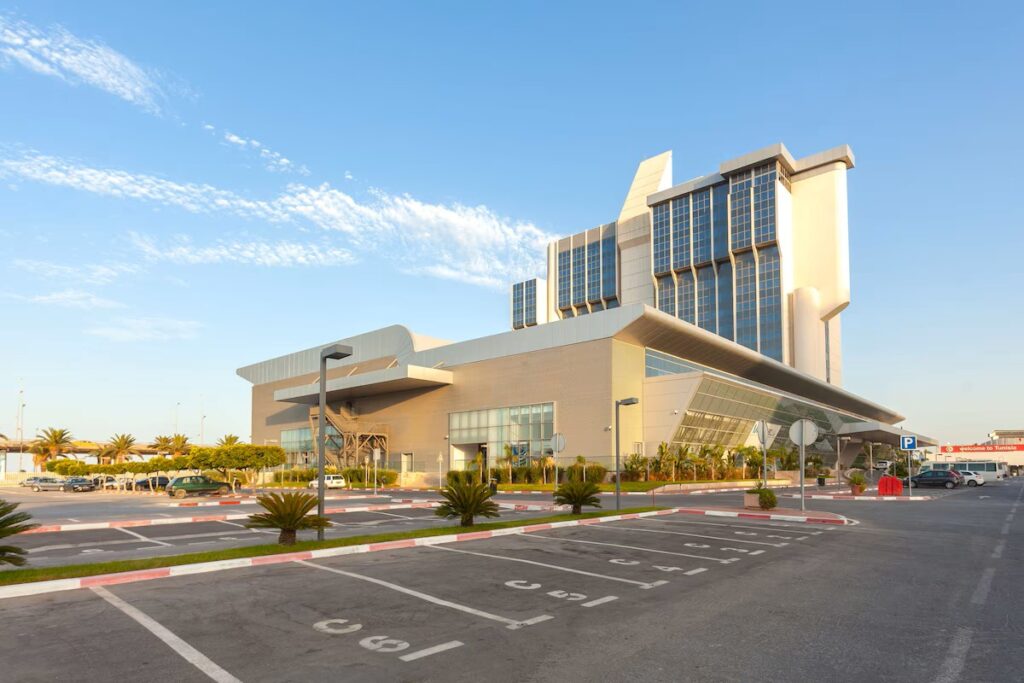 Modern hotel exterior in Tunisia with palm trees and parking area.